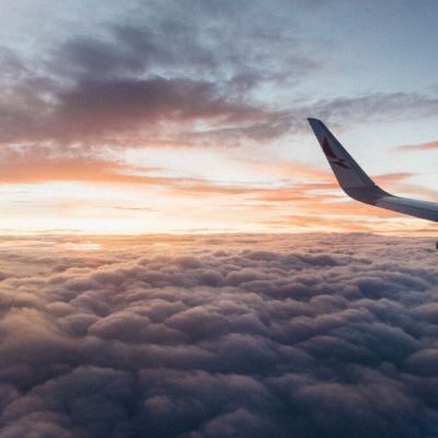 Airplane flying above clouds with sunset in background