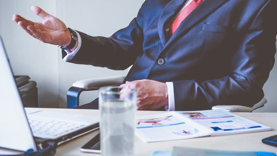 Boss raising his hand in a questioning matter during a meeting