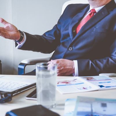 Boss raising his hand in a questioning matter during a meeting