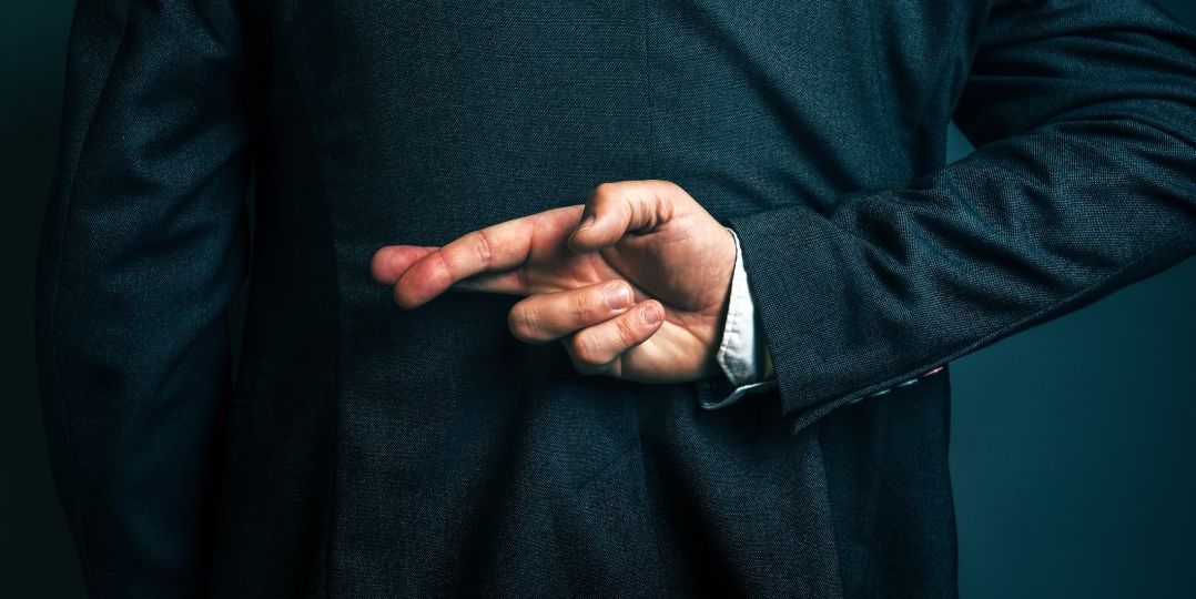 Business man with fingers crossed behind back