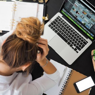 A stressed out worker with her face in her hands while sitting at her desk