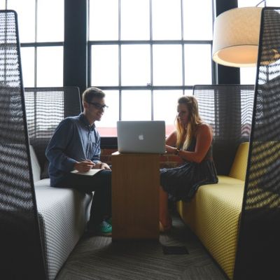 Two people sitting across from each other sharing a laptop and working together