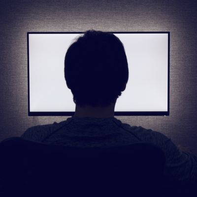 Man sits in front of a blank monitor in dark room